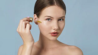 Attractive Young Woman Applying Serum On Her Face . Skin Care Co