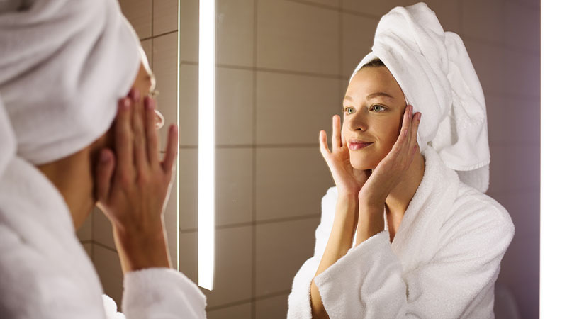 Woman Looking On Her Mirror In Bathroom