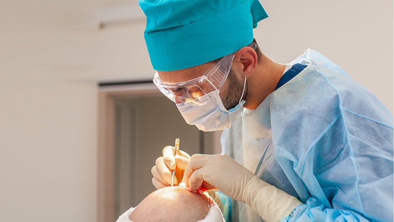 Baldness Treatment. Hair Transplant. Surgeons In The Operating Room Carry Out Hair Transplant Surgery. Surgical Technique That Moves Hair Follicles From A Part Of The Head.