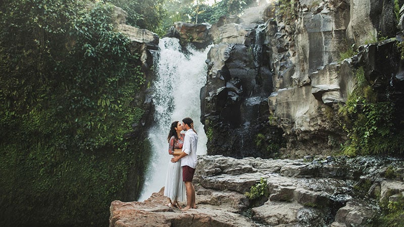 Jeune couple s'embrassant avec vue cascade. Heureux ensemble, lune de miel à Bali