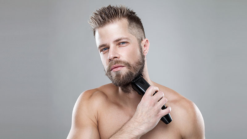 Handsome Bearded Man Trimming His Beard With A Trimmer