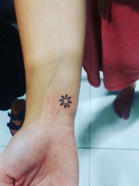 Tiny white ink sun tattoo.