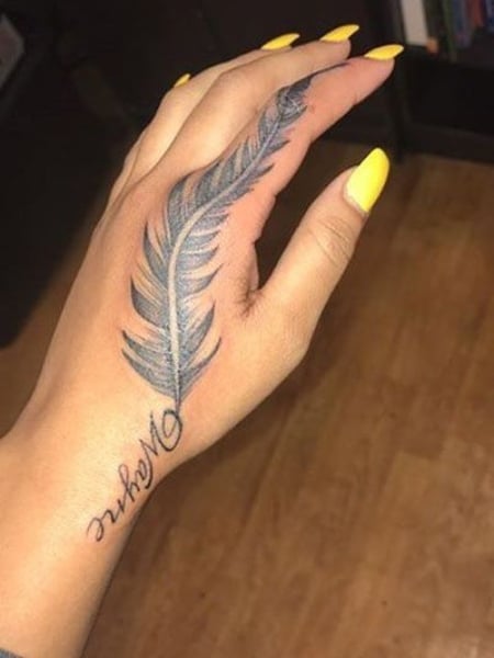 Rita Oras Delicate Feather Tattoo on Her Hand PopStarTats