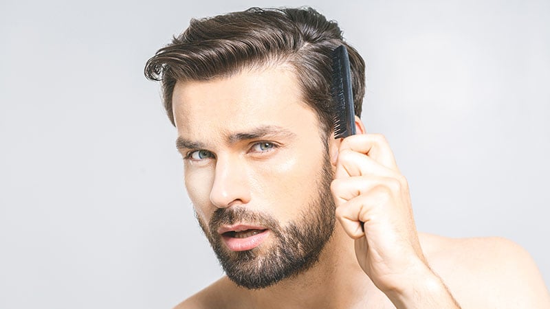 Portrait Of Handsome Young Man Combing His Hair In Bathroom. Iso