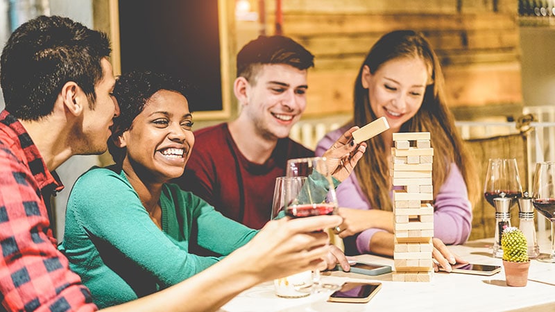 Young Friends Playing Board Games At Hostel Living Room Divers