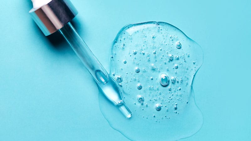 Pipette With Dose Of Fluid Hyaluronic Acid On Blue Background