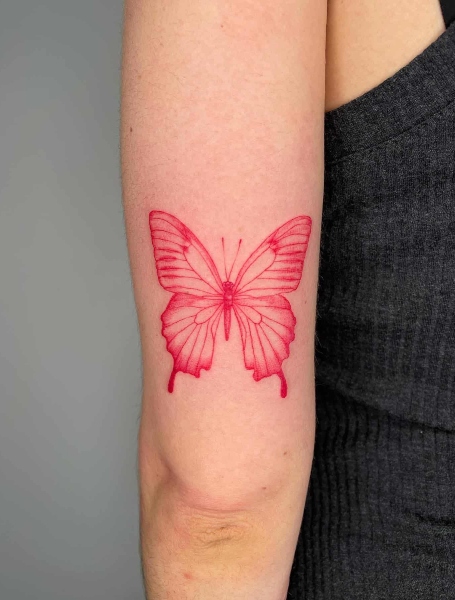 Red butterfly tattoo located on the inner forearm