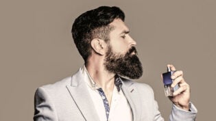 Perfume Or Cologne Bottle And Perfumery, Cosmetics, Scent Cologne Bottle, Male Holding Cologne. Masculine Perfume, Bearded Man In A Suit. Masculine Perfume, Bearded Man In A Suit