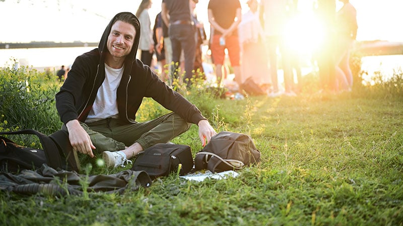 Happy And Smiling Man Sitting By Himself Outside In The Grass Wh